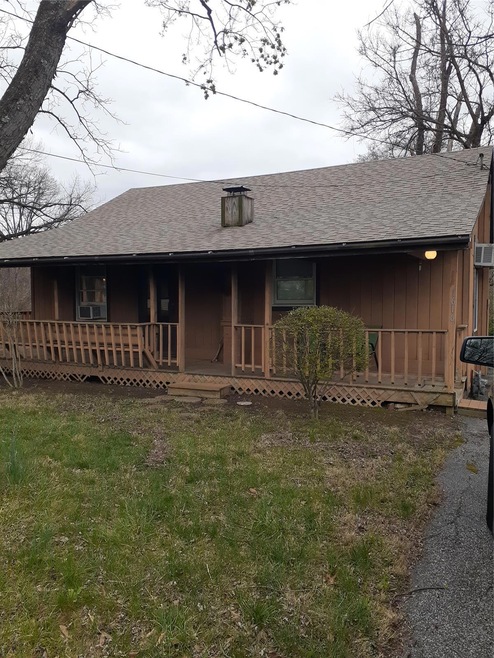 View of front facade with a shingled roof and covered porch