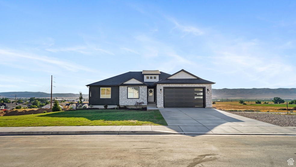 View of front facade with driveway, a mountain view, an attached garage, and a front lawn