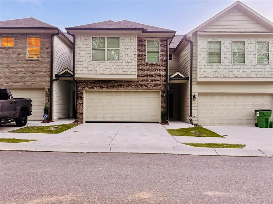 Townhome / multi-family property with a garage, concrete driveway, and brick siding