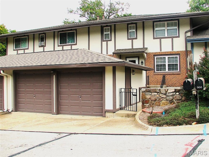 View of front facade featuring brick siding, roof with shingles, driveway, and an attached garage