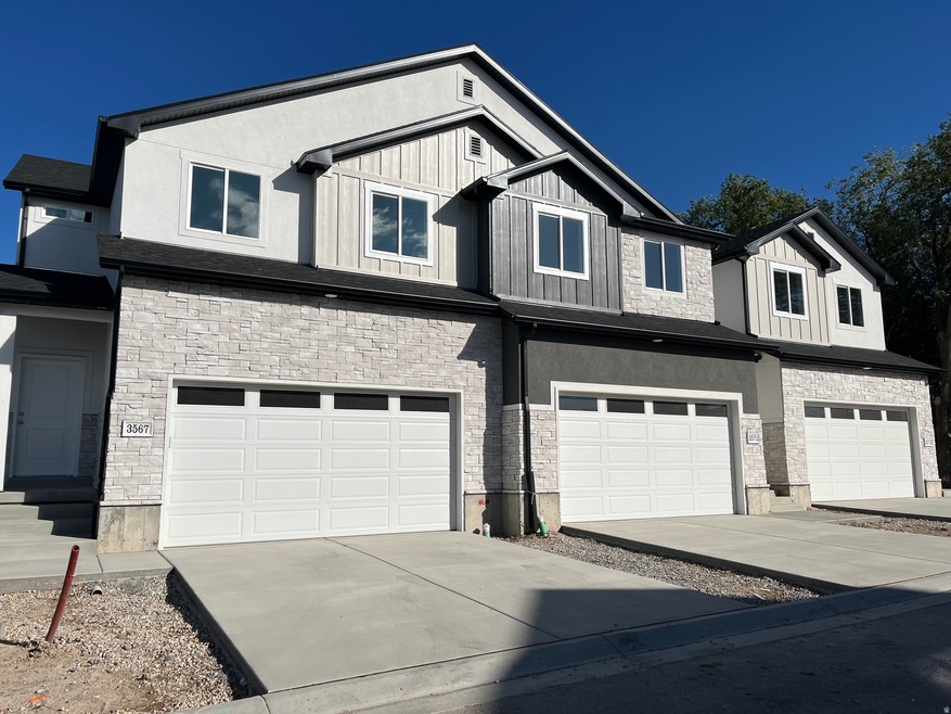 View of front facade with stone siding, driveway, a garage, and board and batten siding
