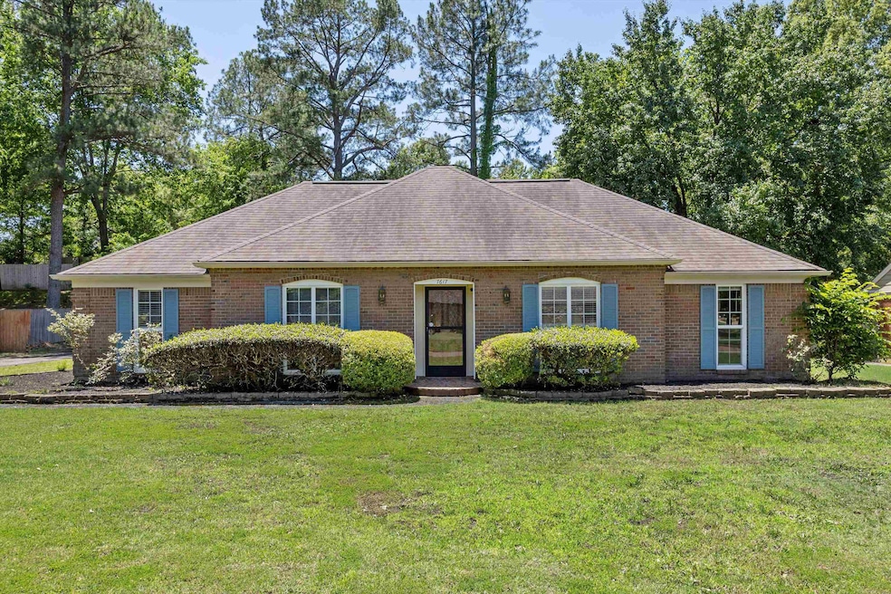 View of front of property with a front lawn, roof with shingles, and brick siding