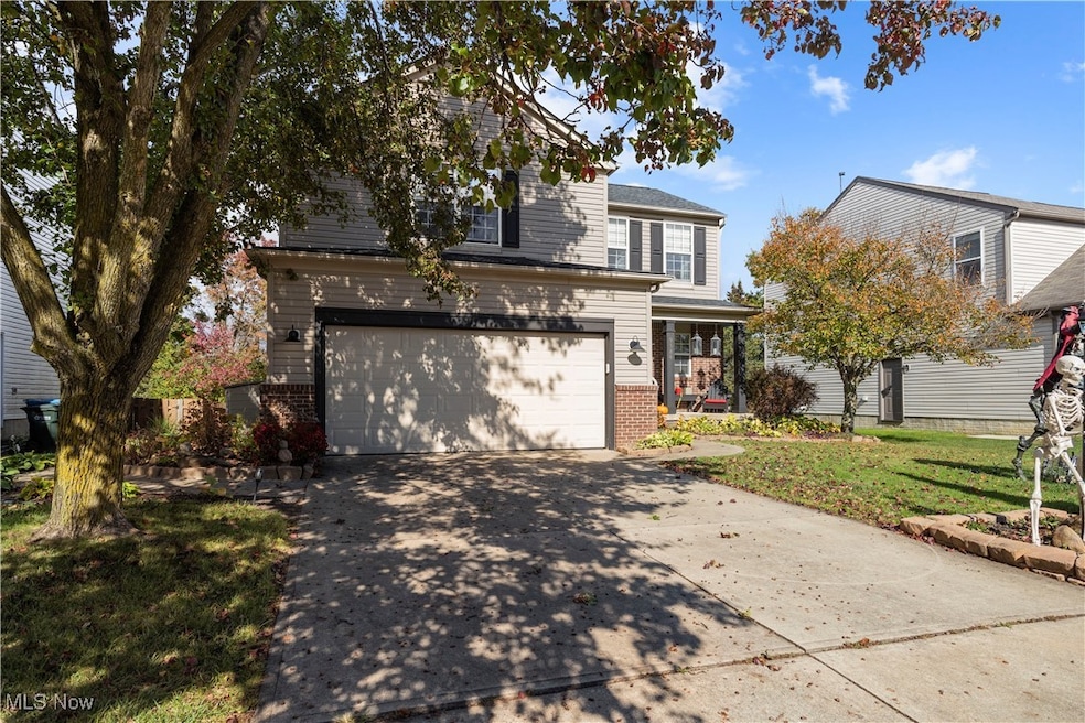 Traditional-style home featuring driveway, brick siding, a front lawn, and covered porch