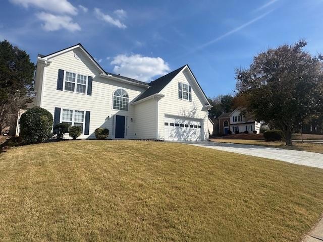 Traditional-style home with a front yard, concrete driveway, and a garage