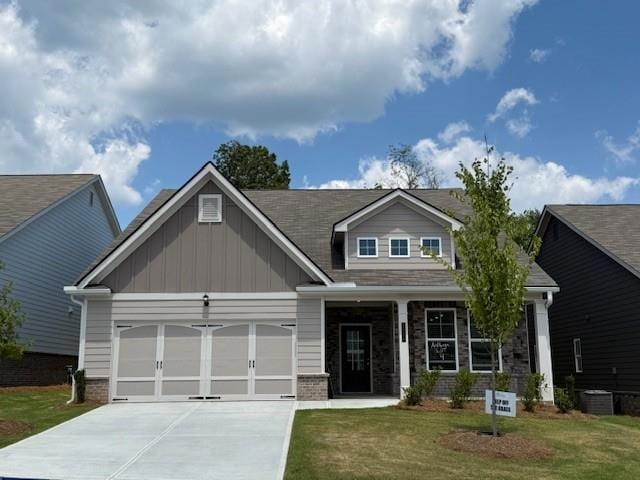 Craftsman inspired home with board and batten siding, an attached garage, concrete driveway, a front yard, and covered porch
