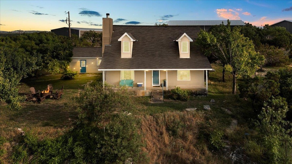 View of front of home featuring a chimney, covered porch, roof with shingles, and an outdoor fire pit