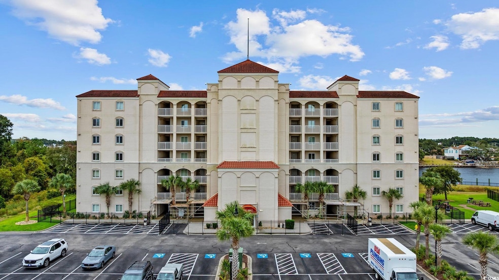 View of apartment building / complex with uncovered parking and a water view