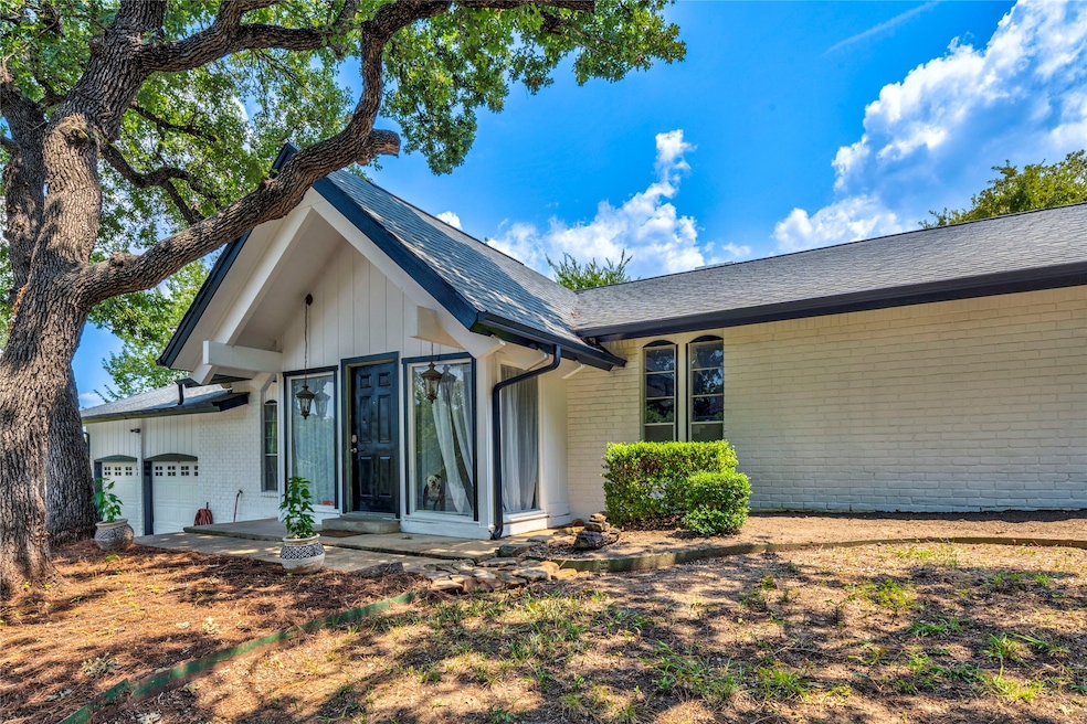 View of front of property featuring brick siding, a garage, and roof with shingles