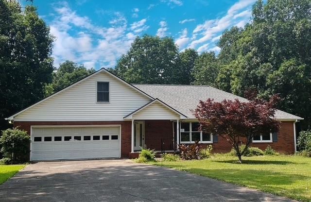 Traditional home with driveway, a front yard, brick siding, and an attached garage