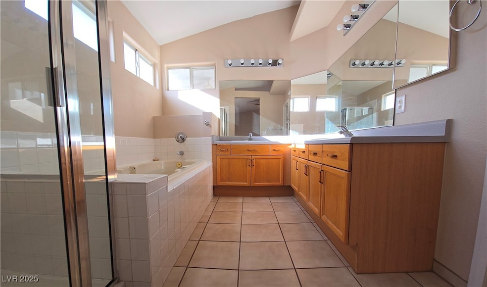 Full bath with vanity, lofted ceiling, a bath, til