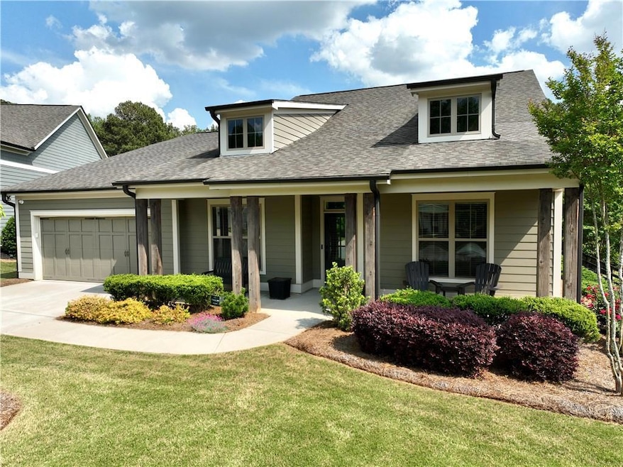 View of front of property with a garage, a front lawn, covered porch, driveway, and roof with shingles