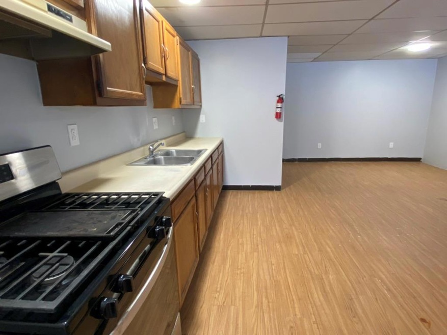Kitchen featuring a drop ceiling, sink, light hardwood / wood-style flooring, and stainless steel gas stove