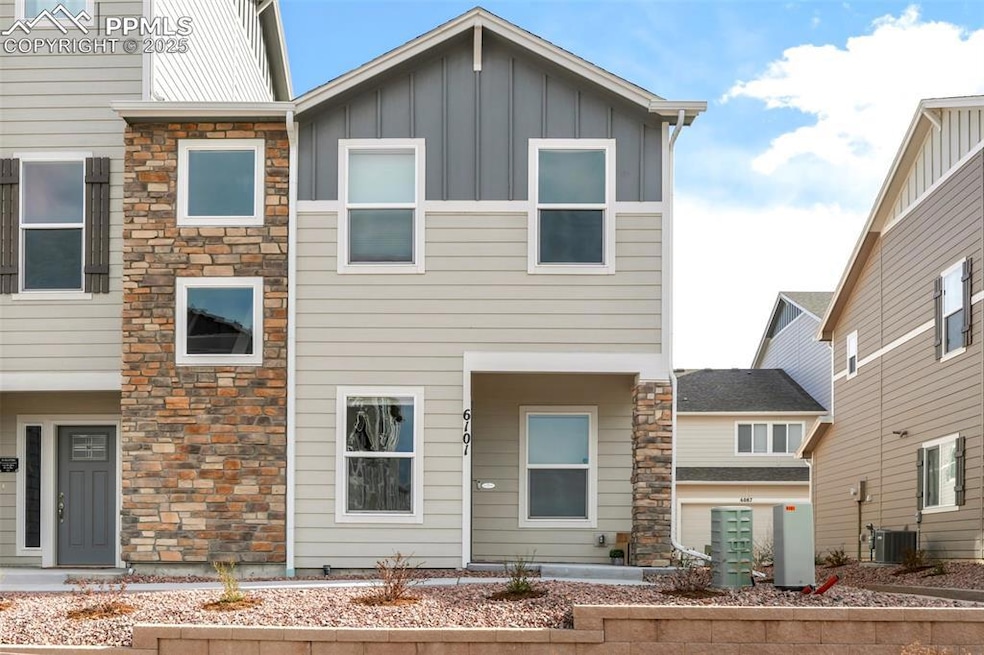 View of front of property with stone siding, central air condition unit, and board and batten siding