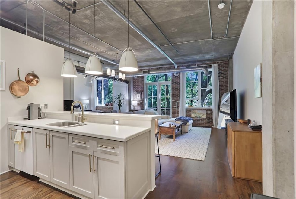 Kitchen featuring decorative light fixtures, a peninsula, dark wood-style floors, and open floor plan