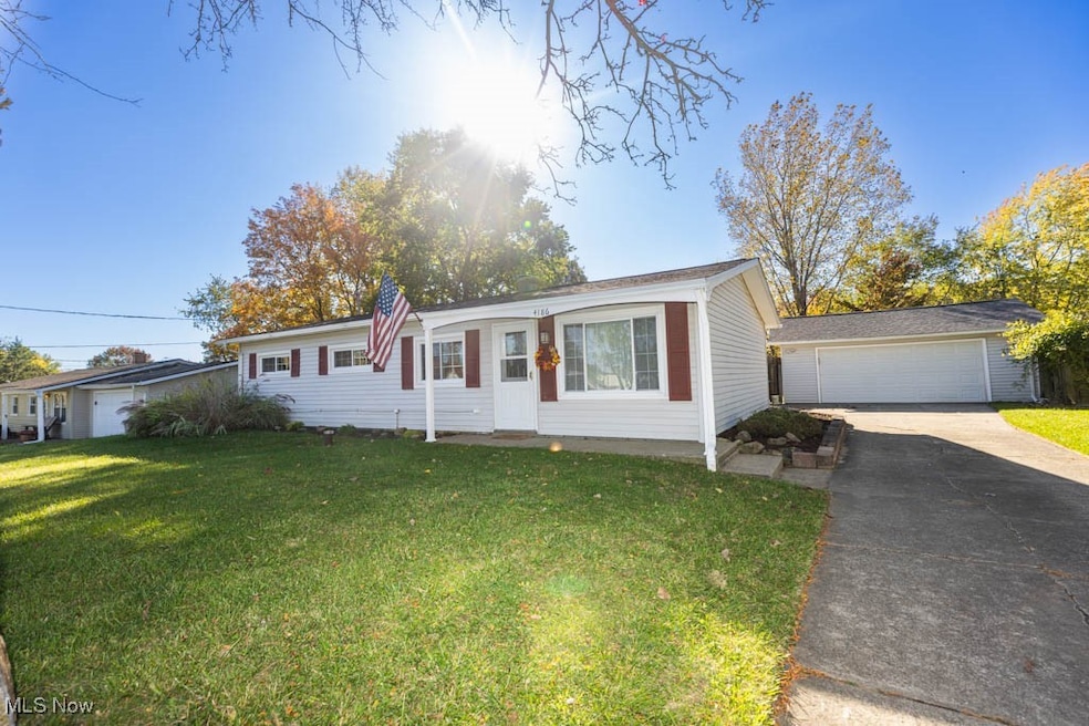 Ranch-style house featuring a front lawn, a garage, an outbuilding, and concrete driveway