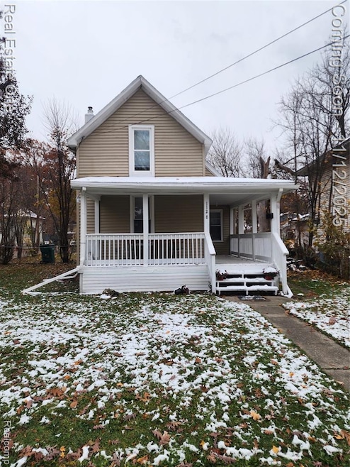 View of front facade featuring covered porch and a chimney