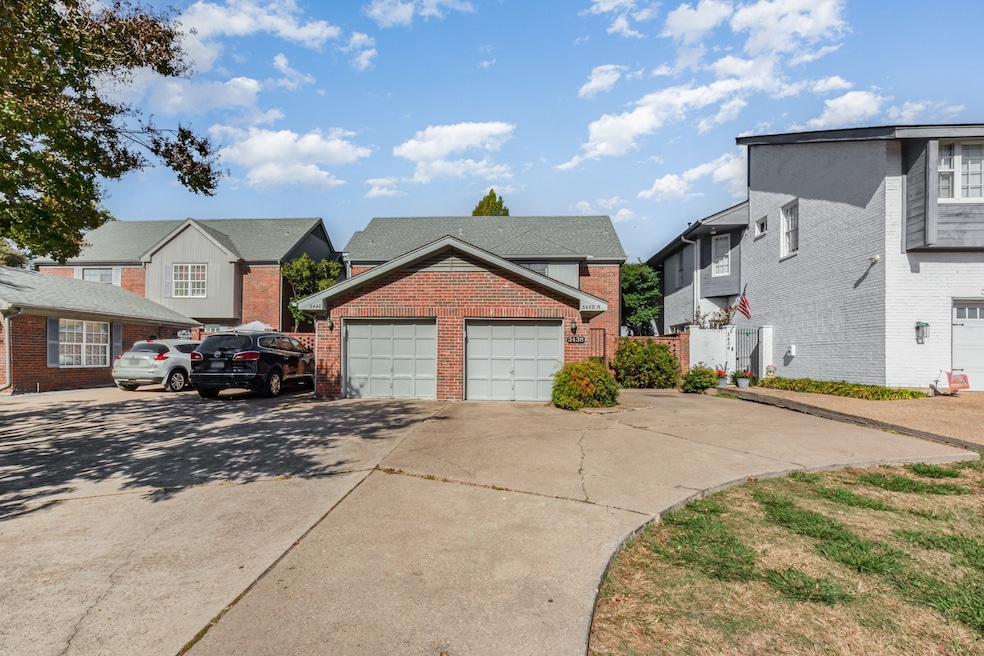 View of front of property featuring a garage, brick siding, a residential view, and driveway