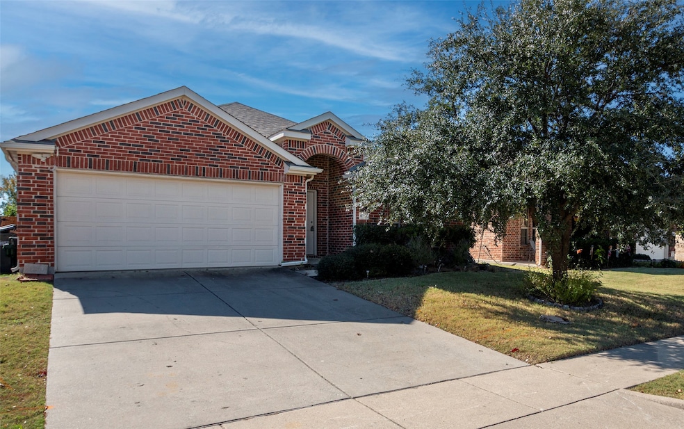 View of front facade featuring concrete driveway, brick siding, an attached garage, and a front yard