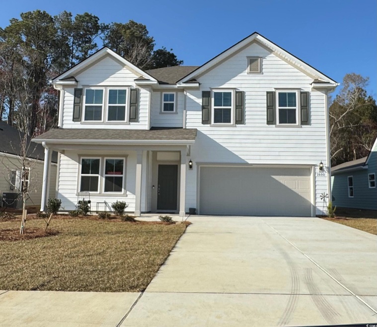 Traditional home featuring driveway, a shingled ro