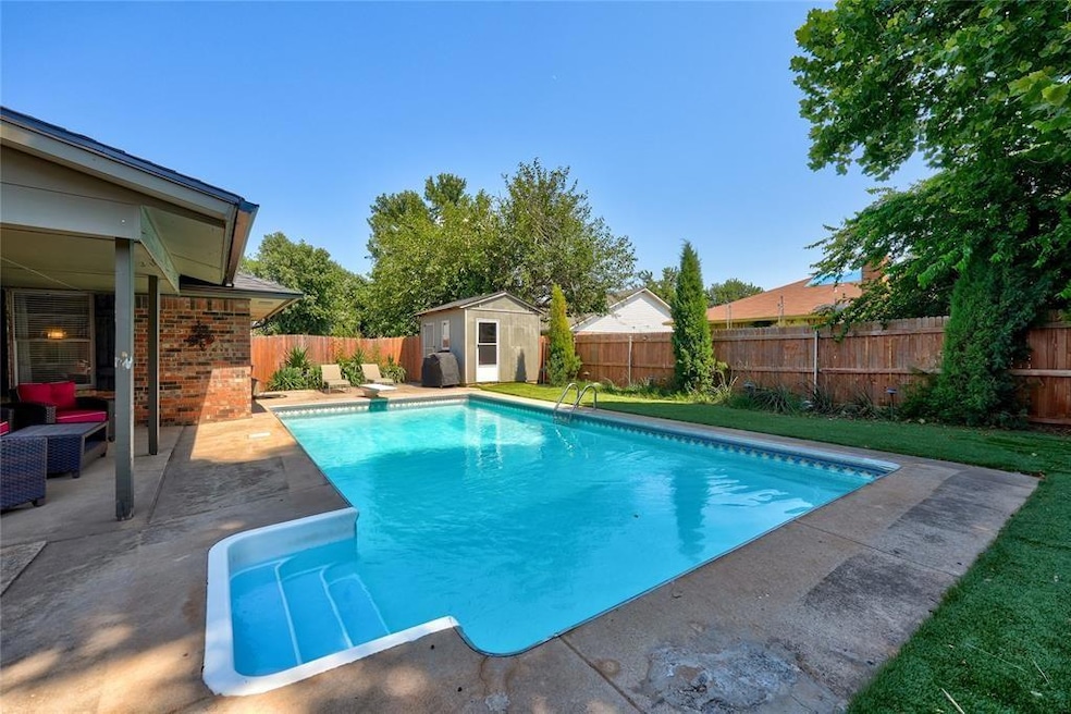 View of pool when uncovered featuring a fenced backyard, a patio area, a storage shed, and a diving board