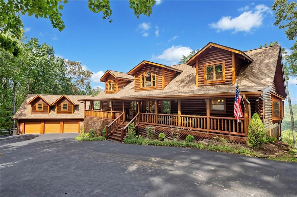 Log home featuring a garage, covered porch, an out