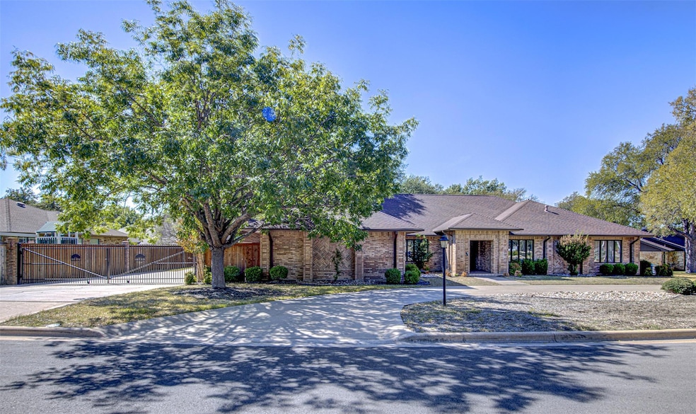 View of front of home with brick siding, a gate, driveway, and a shingled roof