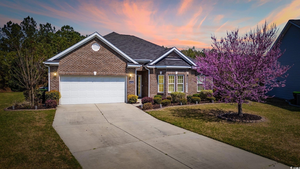 View of front of house with brick siding, concrete driveway, and a yard