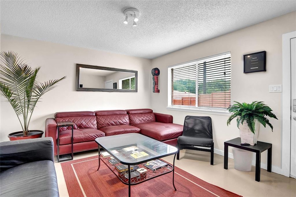 Living room with a textured ceiling and baseboards