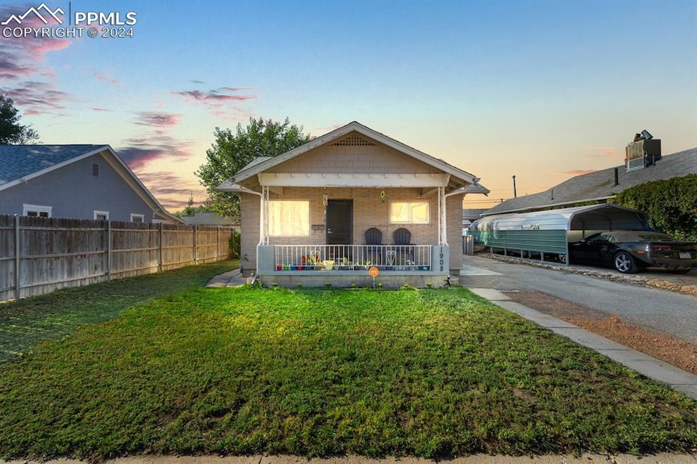 View of front of property featuring a porch, a carport, and a lawn