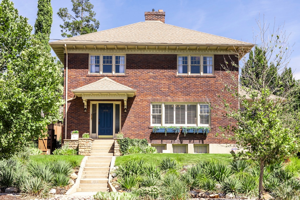 View of front facade with a chimney, a shingled roof, and brick siding