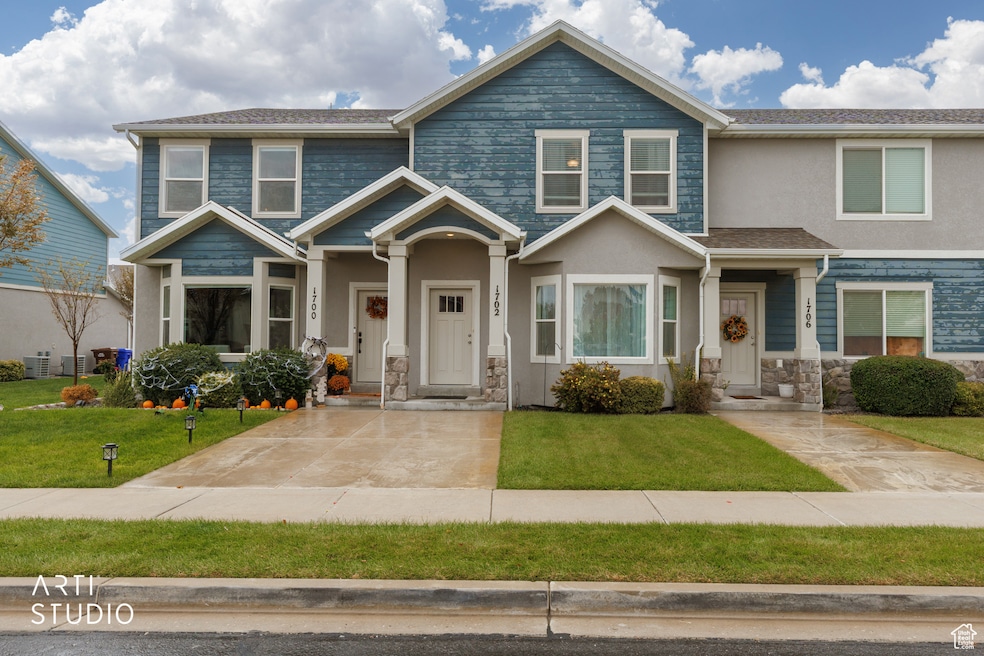 View of front of house featuring stone siding, a front yard, and stucco siding