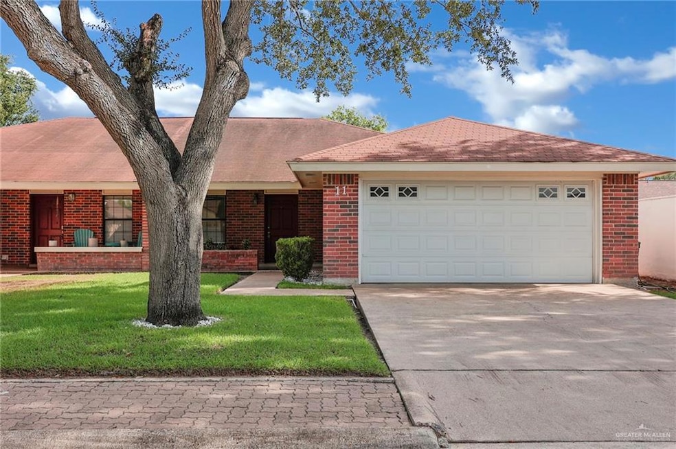 View of front of home featuring driveway, brick siding, a front yard, and a garage
