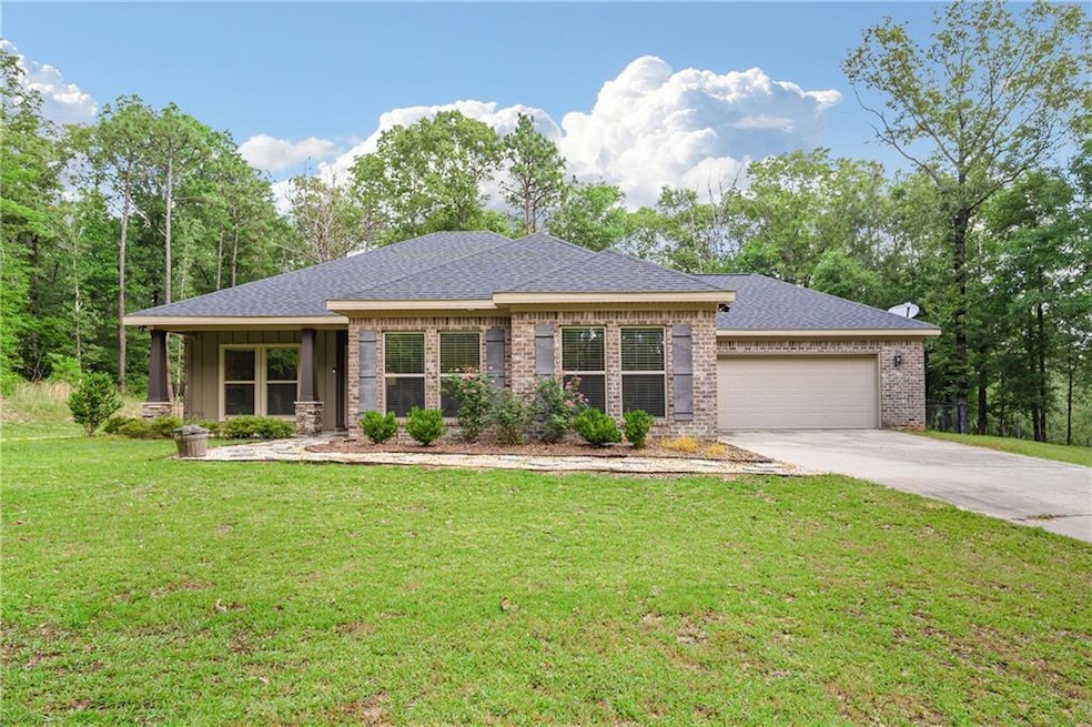 View of front of property featuring concrete driveway, an attached garage, a front lawn, roof with shingles, and brick siding