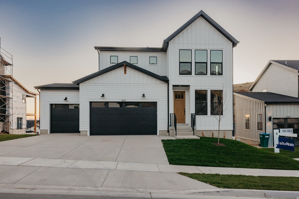 Modern farmhouse with a yard, concrete driveway, a garage, and board and batten siding