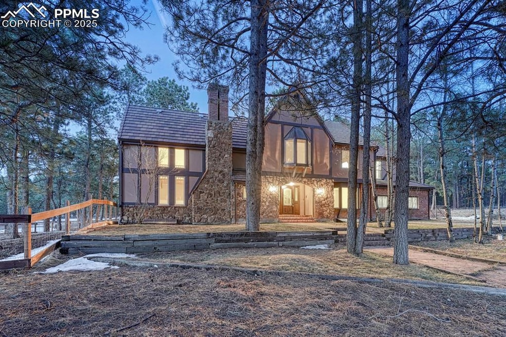 Back of property featuring stone siding and a chim