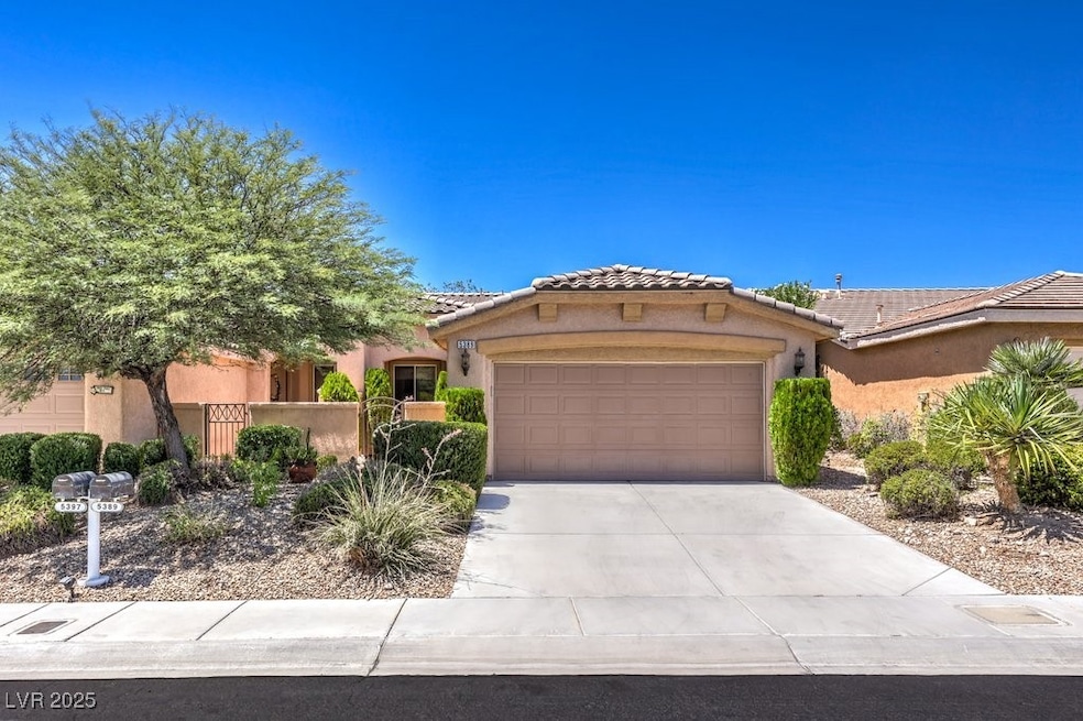 View of front facade featuring stucco siding, a tile roof, an attached garage, and driveway