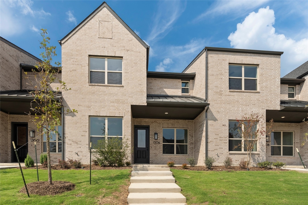 View of front of property with a standing seam roof, brick siding, and a front lawn