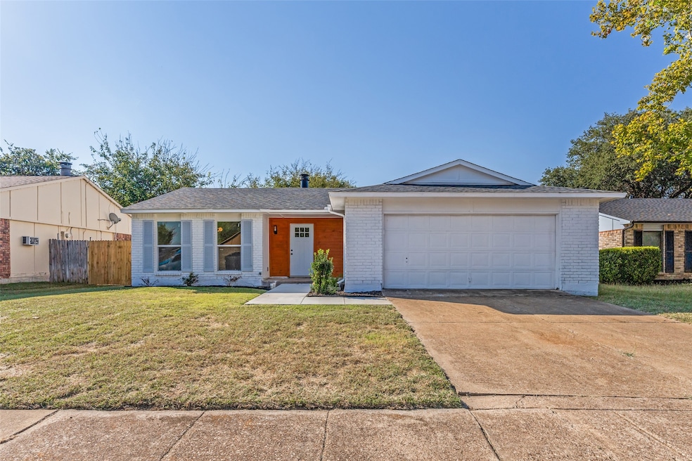 View of front of house with brick siding, driveway, and roof with shingles