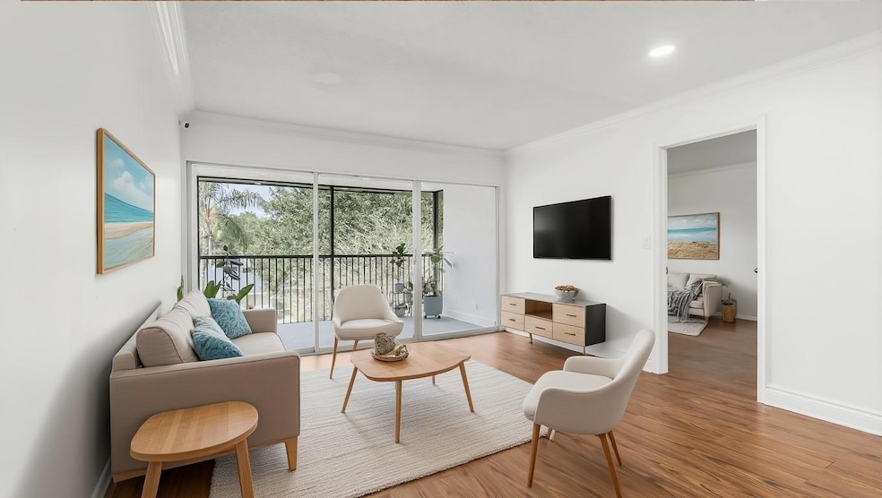 Bright living room with wood vinyl flooring neutral paint and crown molding- Virtually Staged.