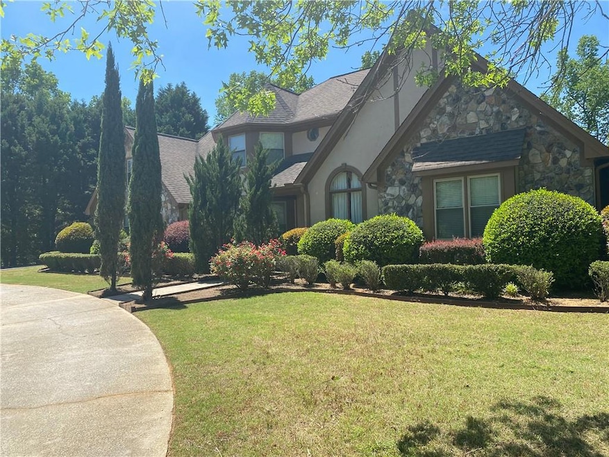 Tudor home featuring stone siding, a front lawn, and stucco siding