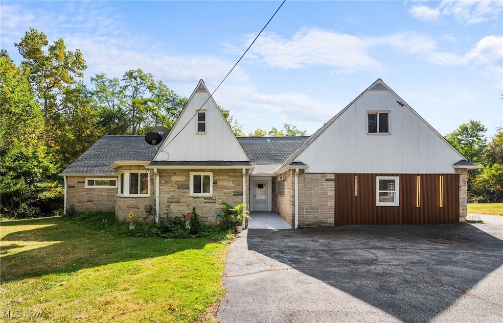 View of front facade featuring a front lawn and stone siding