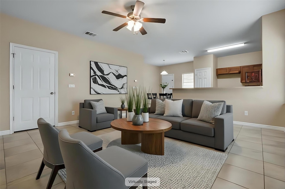 Living area with ceiling fan, light tile patterne