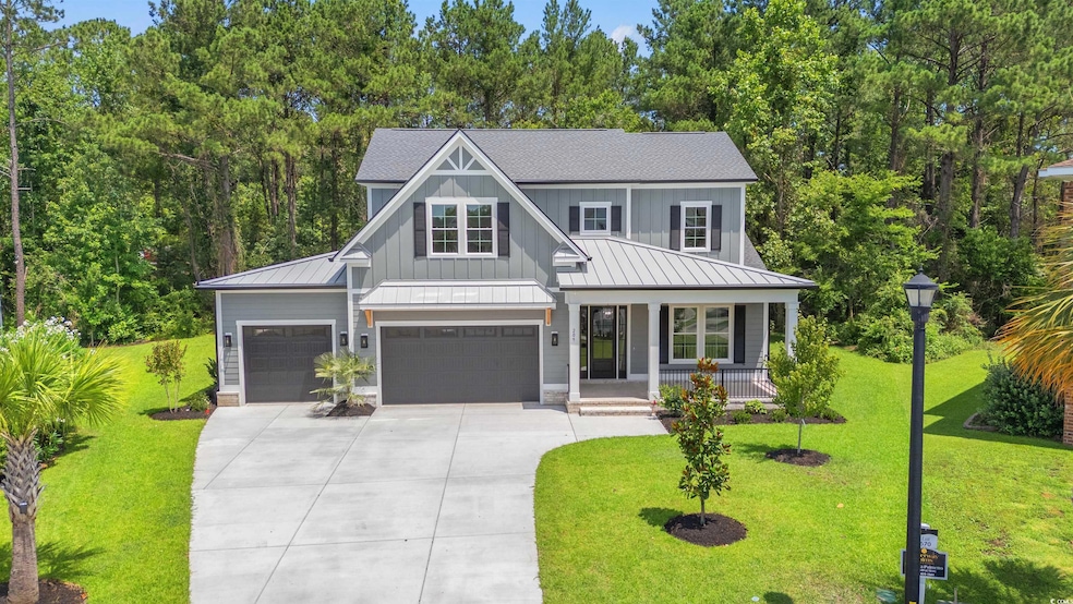 Modern farmhouse featuring a porch, a standing seam roof, concrete driveway, a front yard, and board and batten siding