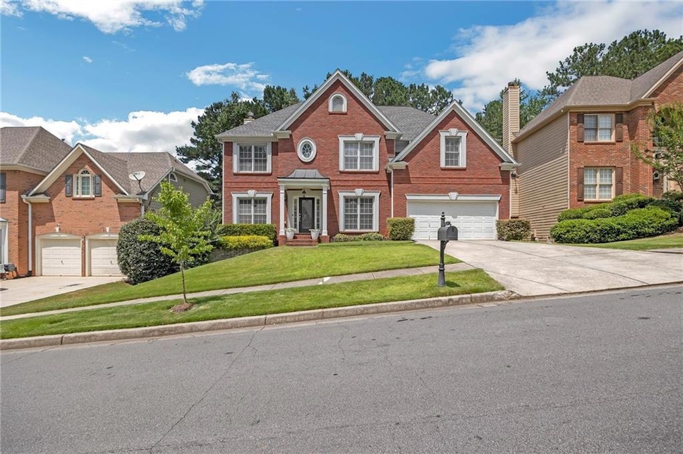 Colonial inspired home with concrete driveway, an attached garage, a front yard, and brick siding