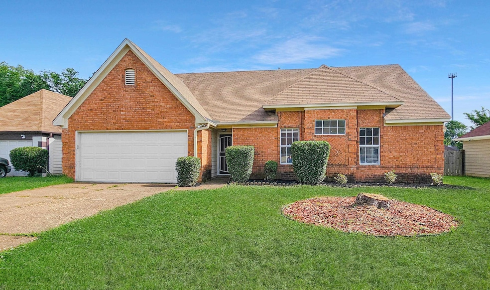 View of front of property featuring concrete driveway, a front yard, brick siding, and an attached garage