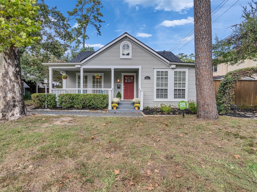 Charming classic cottage with a welcoming front porch, surrounded by mature trees and well-maintained landscaping. Features classic shutters and a cheerful red door, offering a cozy and inviting curb appeal.