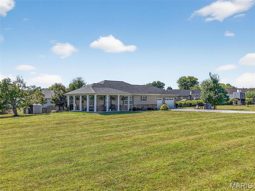 Ranch-style house featuring a front yard, a garage, driveway, and covered porch