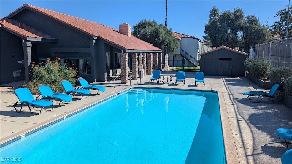 Community pool featuring a patio area and a shed