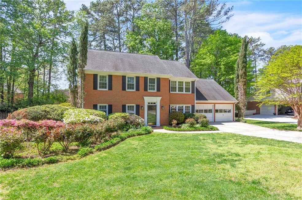 Colonial house with concrete driveway, a front lawn, brick siding, and a garage
