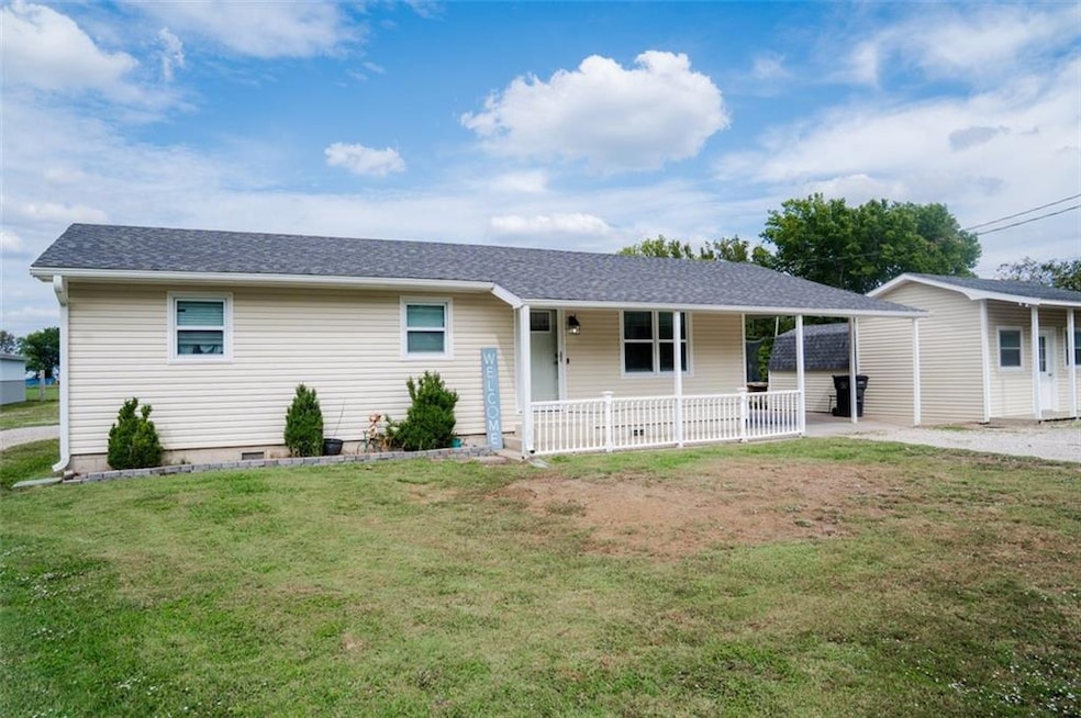 Ranch-style house featuring a front lawn, roof with shingles, and a patio